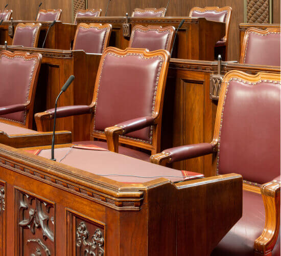 Gros plan des chaises et des bureaux des sénateurs dans la salle du Sénat